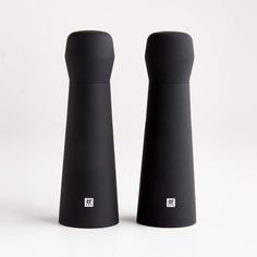 two black salt and pepper shakers sitting side by side