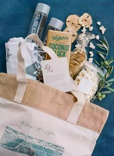 a tote bag filled with various items on top of a blue surface next to flowers