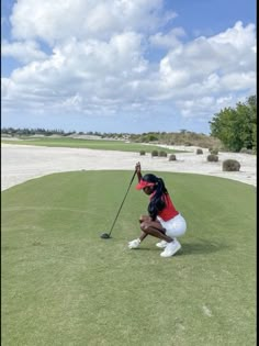 a woman kneeling down on top of a green golf field