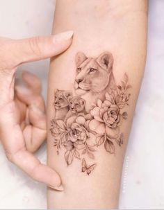 a woman's arm with a lion and flowers tattoo on it