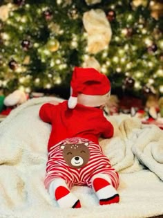 a teddy bear laying on top of a blanket next to a christmas tree