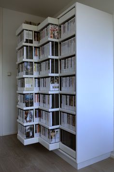 a white book shelf filled with lots of books on top of a hard wood floor