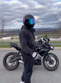 a person wearing a helmet standing next to a motorcycle