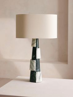 a lamp that is sitting on top of a white table with a black and white base