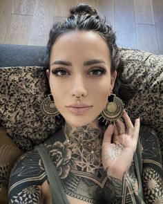 a woman with tattoos on her chest sitting in a chair and looking at the camera