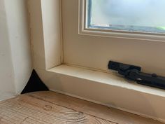 an open window with a black handle on the side of it next to a wooden floor