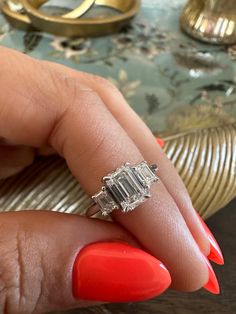 a woman's hand with red nail polish and an engagement ring on her finger