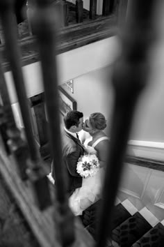 a bride and groom are kissing on the stairs at their wedding reception in black and white