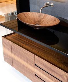 a wooden bowl sink sitting on top of a counter next to a wall mounted mirror