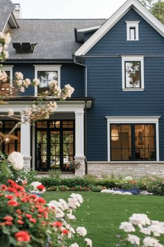 a blue house with lots of flowers in the front yard