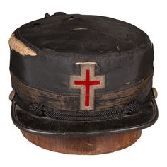 ABOUT  An original Masonic Knights Templar hat with silver and red cross. The leather brim is trimmed with rope and brass buttons. Hat block not included.      CREATOR The McLilley & Co., Columbus, Ohio.      DATE OF MANUFACTURE c.1800s.     MATERIALS AND TECHNIQUES Silk, Leather, Brass.      CONDITION Distressed. Wear consistent with age and use.     DIMENSIONS H 3.5 in. D 7 in. W 9.75 in.  HISTORY  Unknown. Hat Blocks, Brass Buttons, Columbus Ohio, Red Cross, Columbus, Ohio, Collectibles, Brass, The Originals