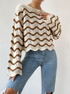 a woman wearing ripped jeans and a sweater with an openwork design on the shoulders