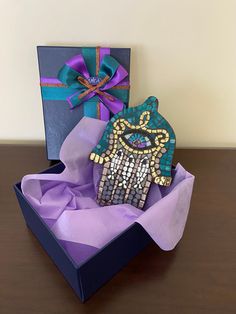 a gift box with a hamsa and purple ribbon