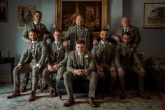 a group of men sitting next to each other in front of a painting on the wall