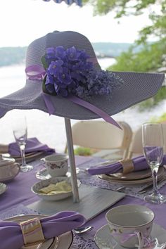 a purple hat on top of a table next to plates and cups with napkins