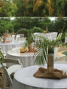 tables with white linens and palm trees in the background at a wedding reception venue