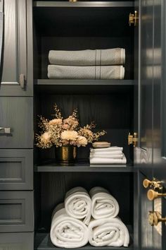 towels and flowers are on the shelves in this walk - in closet with gray cabinets