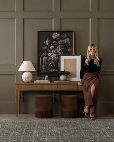 a woman sitting on a bench next to a table with two vases and pictures