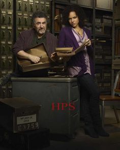 two people standing next to each other in a room full of files and boxes with the words hps written on them