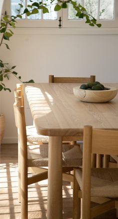 a wooden table with two chairs and a bowl of green beans on top of it