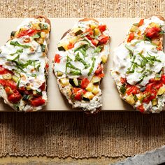 three slices of bread topped with vegetables and sour cream on a cutting board next to a knife