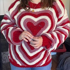 a woman wearing a red and white sweater with a crocheted heart on it