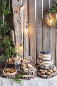 a table topped with cakes and desserts covered in frosting next to a wooden fence