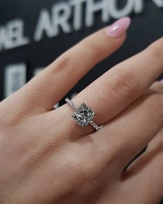 a woman's hand with a diamond ring on top of her finger and pink nail polish