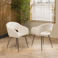 two white chairs sitting next to each other in front of a window