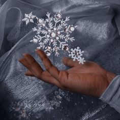 a person's hand holding a snowflake ornament in their palm