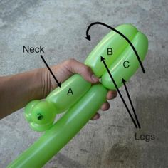 a person holding an inflatable green object with the letters abc and c on it