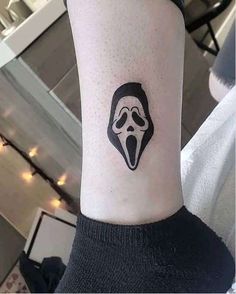 a person with a black and white mask tattoo on their arm