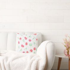 a white couch sitting next to a table with a vase on it and a pillow