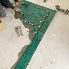 two men are working on a piece of green tile