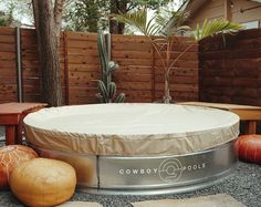 an outdoor hot tub in the middle of a yard with two stools next to it