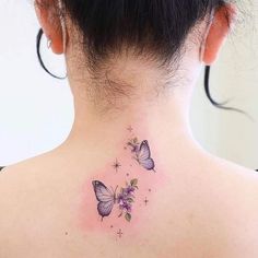 the back of a woman's neck with two butterflies and stars tattoo on it