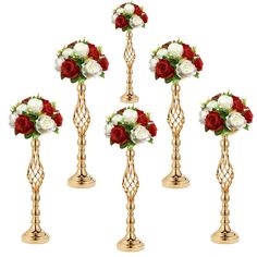 four gold candlesticks with red and white flowers in them on a white background