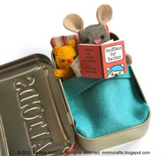 a stuffed mouse in a tin with a book