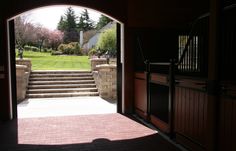 an open door leading to a lush green yard with trees in the back ground and stairs on either side