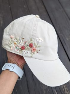 a person wearing a white hat with flowers embroidered on the front and side of it