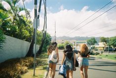 three girls are walking down the street with their backs to each other and one has her hand on her hip