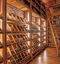 a room filled with lots of books on wooden shelves next to a brick wall and floor