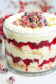 a cake with white frosting and berries on top is sitting in a glass dish