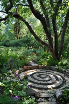 a stone path in the middle of a garden surrounded by trees and flowers, with a spiral design on it