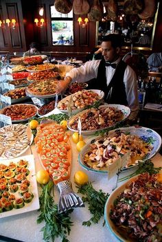 a buffet table filled with lots of different types of food on plates and serving utensils