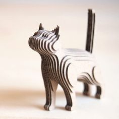 an animal made out of wood sitting on top of a white table next to another animal