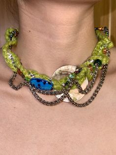 a woman wearing a green necklace with blue beads on it's neck and back