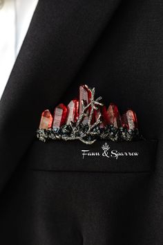 a close up of a suit jacket lapel pin with red stones and leaves on it