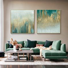 a living room with green couches and paintings on the wall above them, along with a coffee table