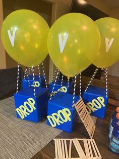 balloons and boxes with the word drop on them are sitting on a table in front of some water bottles